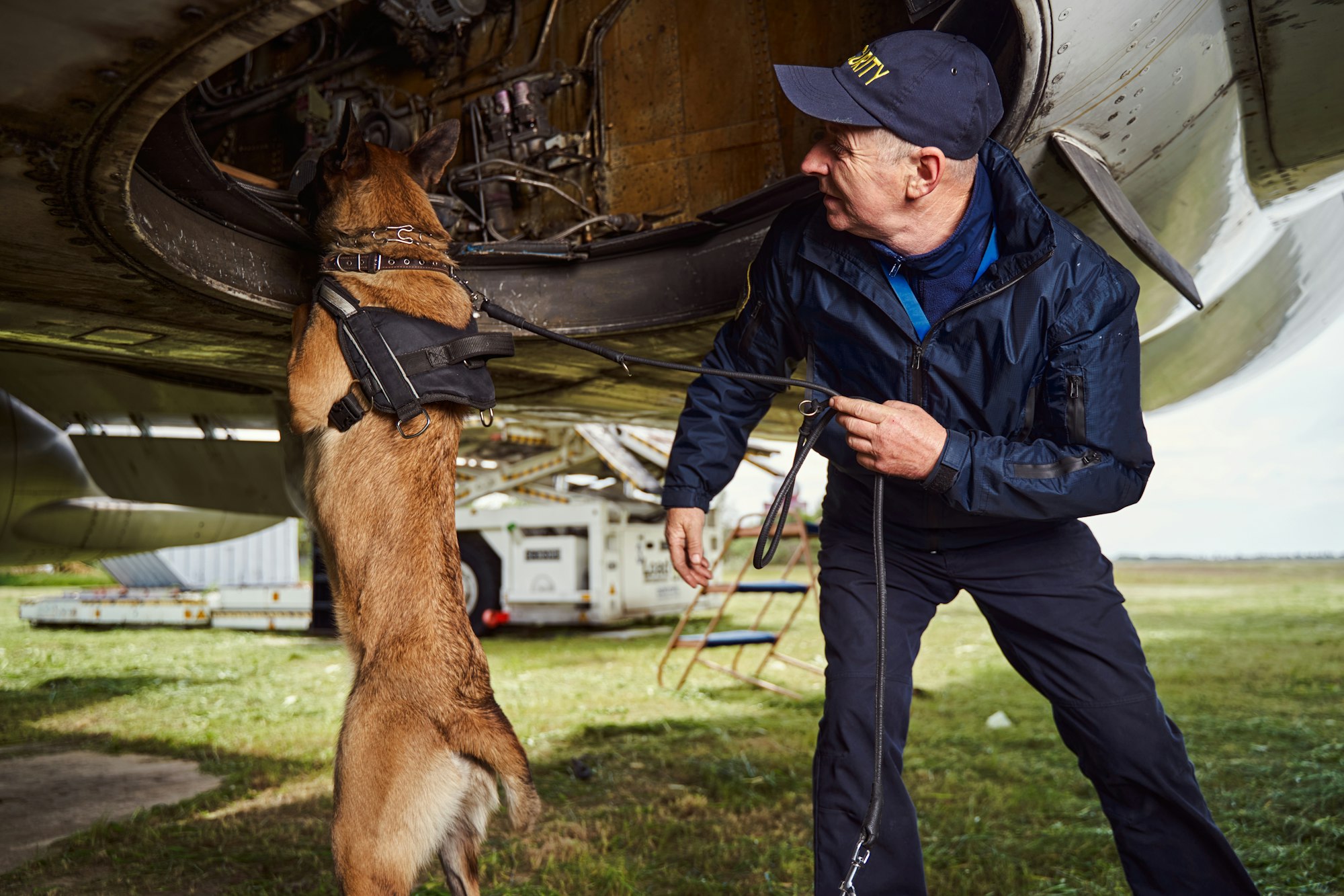 Security officer and police dog inspecting aircraft at aerodrome